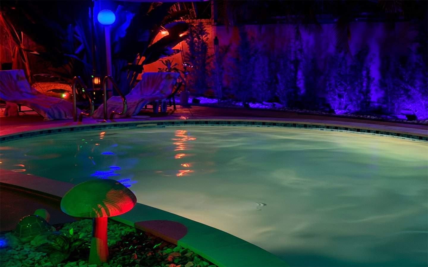 Soft reflections ripple across the heated pool at Garden of Manors, creating a calm, intimate atmosphere enhanced by subtle LED lighting and lush greenery.