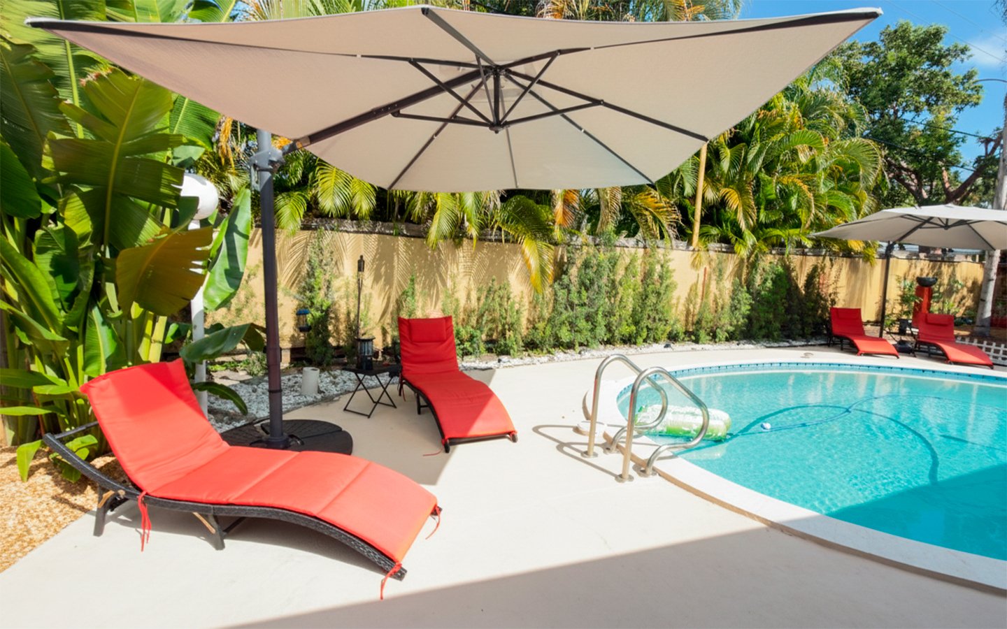 Daytime pool area with shaded loungers and tropical surroundings at Garden of Manors.