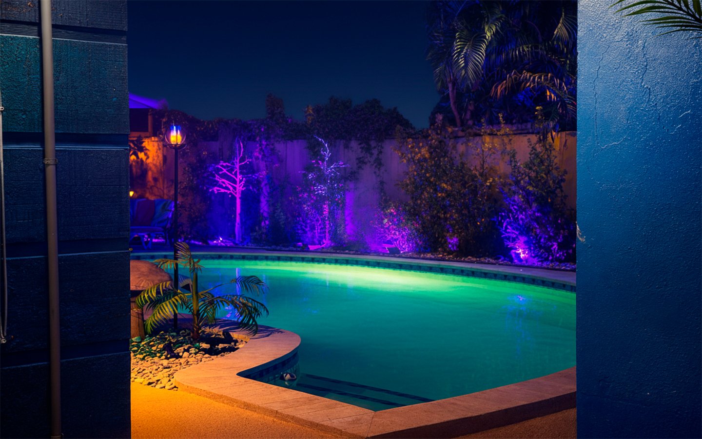 Soft reflections ripple across the heated pool at Garden of Manors, creating a calm, intimate atmosphere enhanced by subtle LED lighting and lush greenery.